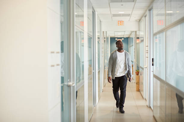 relajado negro freelancer caminando en miami coworking office - acercarse fotografías e imágenes de stock