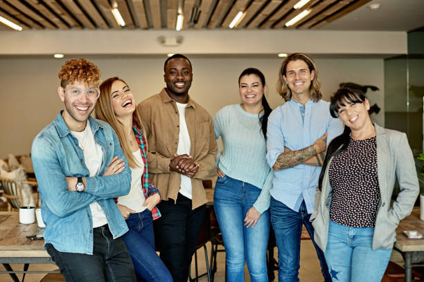 Organized Group Photo of Cheerful and Diverse Business Team Front view of Hispanic, Black, and Caucasian businesspeople wearing casual clothing and smiling at camera as they stand together in Miami coworking office. organized group photos stock pictures, royalty-free photos & images
