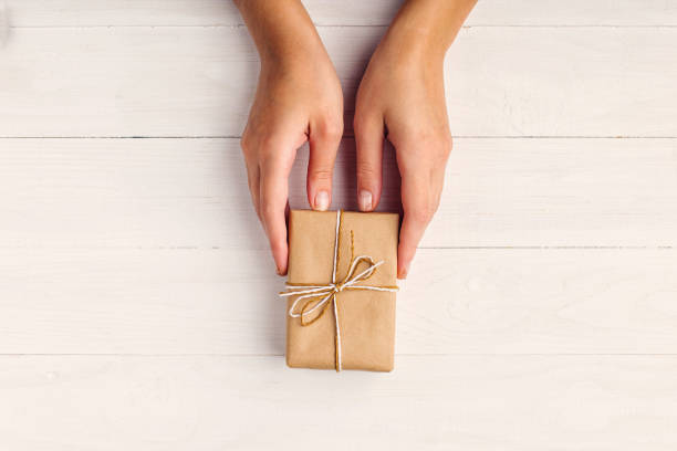 istock Women's hands making a gift from craft paper. 1273251668