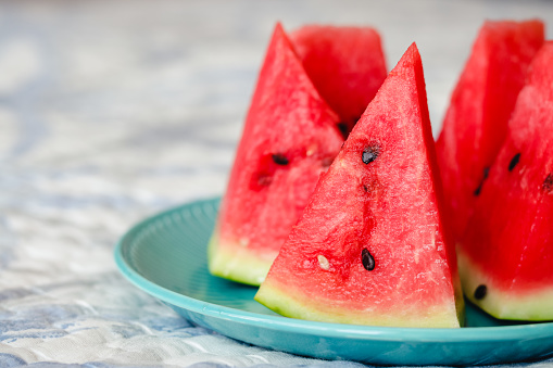 Kherson watermelon cut into triangular pieces on a blue plate