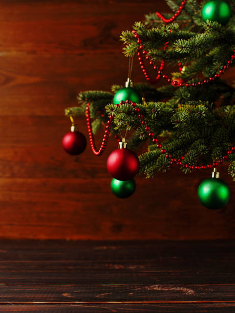 Christmas tree, dressed up balls, stands on a wooden table. Copy space.