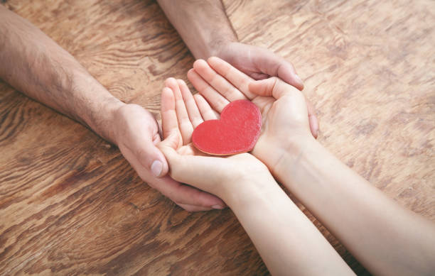 istock Male and female hands holding red heart. 1273254500