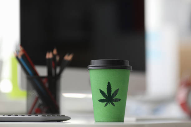 On table is a paper cup with lid painted hemp On table is a paper cup with lid painted hemp. Legalized stand-alone drink with hemp. Flavored organic cocktail. Benefits hemp leaf tea. Cannabis leaf drink without psychoactive effect food sample cups stock pictures, royalty-free photos & images