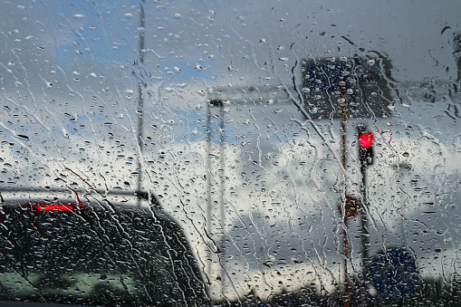 The windshield of a car standing at a traffic light in the rain.