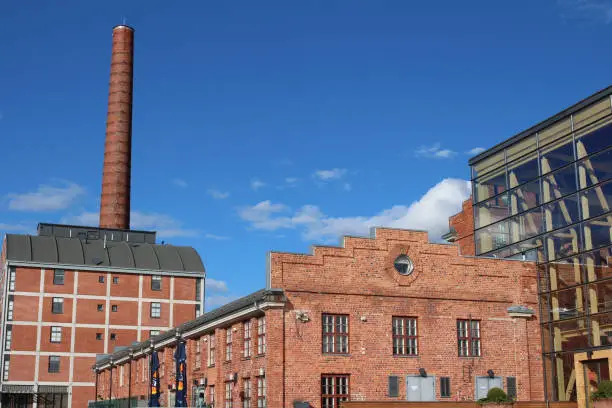 Photo of red brick factory building with a tall chimney in Lahti. Finland.