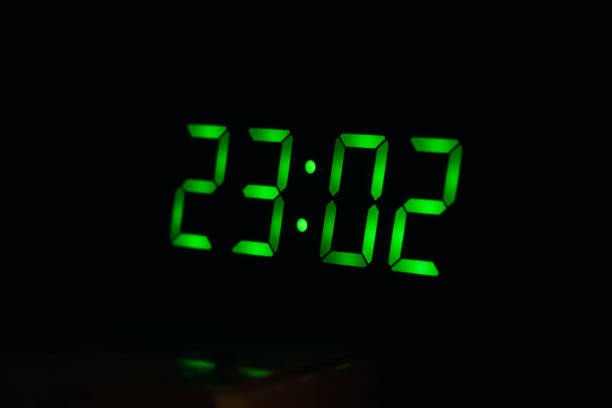 istock Green numbers on electronic watch in dark, midnight 1273256766