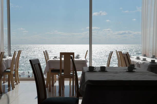 tables de restaurant vides sur le fond de l’horizon de la mer à l’extérieur de la fenêtre - hotel dining room photos et images de collection