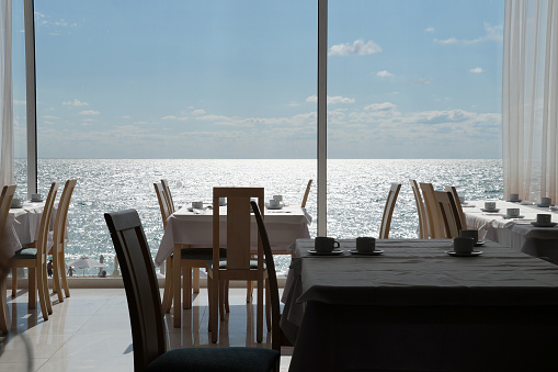 empty restaurant tables on the background of the sea horizon outside the window.