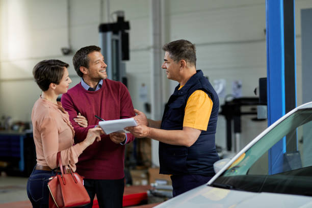 istock Happy couple signing paperwork with auto mechanic in a workshop. 1273264542