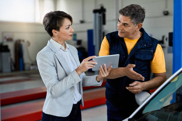 istock Businesswoman and auto repairman using digital tablet in a workshop. 1273264557