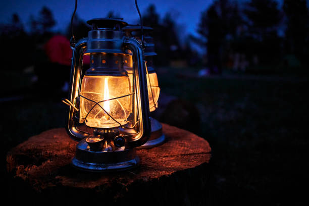 a old rustic oil lantern on a wood block at a camping site - oil lantern imagens e fotografias de stock