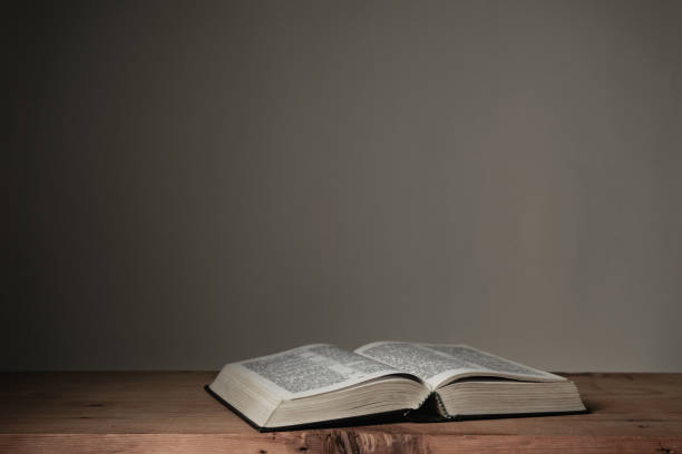 istock Open Holy Bible on a red wooden table and white wall background. Religion concept. 1273267882
