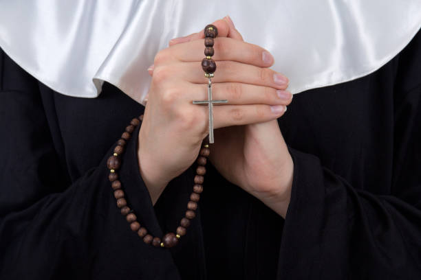 close up of rosary in nun hands stock photo