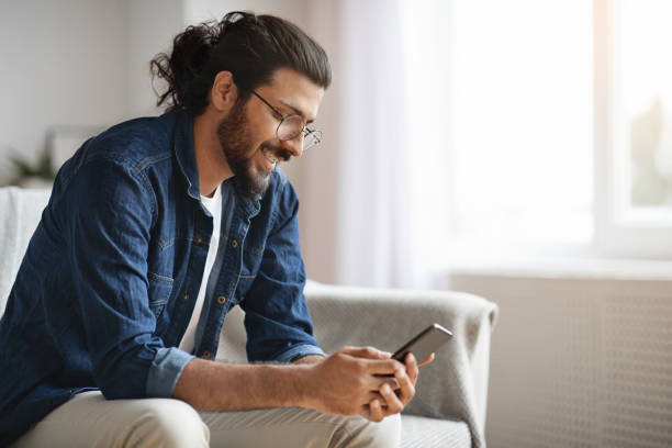 istock New Mobile App. Stylish Western Guy Using Smatphone At Home, Browsing Internet 1273272288