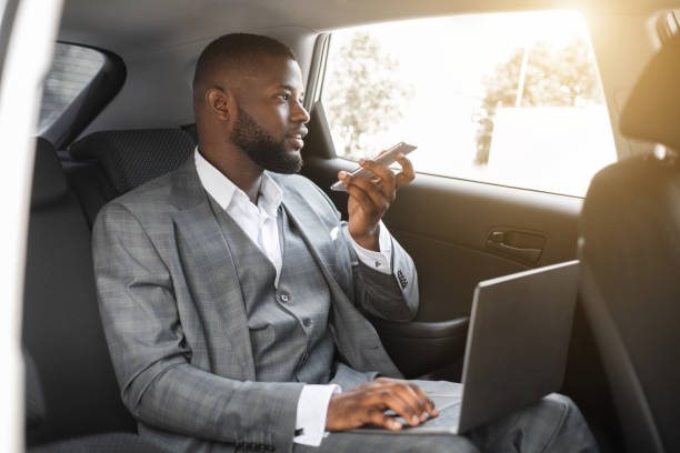 istock Black manager working on laptop in car, using phone 1273272368