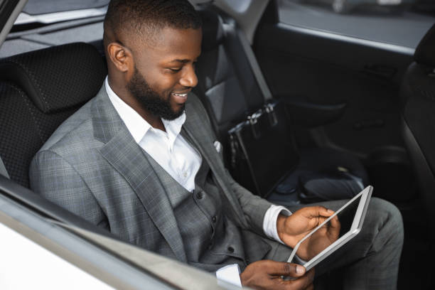 istock Smiling black businessman holding digital tablet in car 1273272550