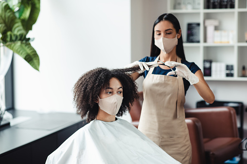 Haircare during pandemic. African american girl cutting split ends at beauty salon, free space