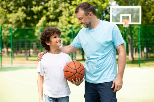 istock Man posing with son on basketball pitch front view 1273272975