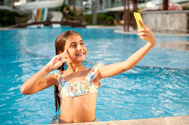 istock Littel girl using mobile phone in the pool 1273274343