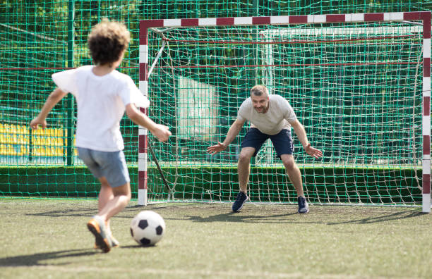 kleiner junge fußballt, ball ins tor kickt - playing field goalie soccer player little boys stock-fotos und bilder