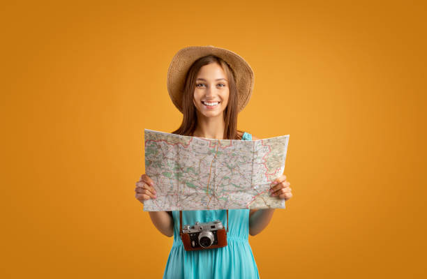 istock Cheerful young woman with camera and city map 1273276050