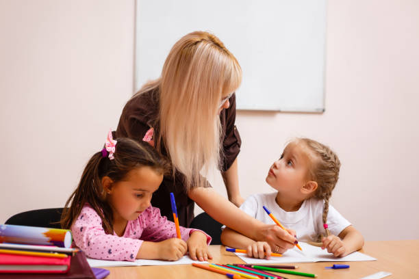istock two happy little schoolgirls study in class, the teacher explains 1273277194