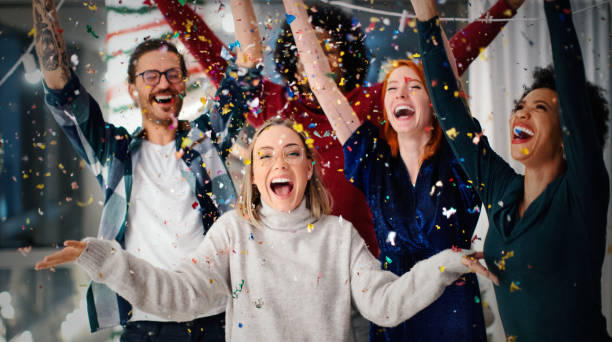 Happy New Year!!! Group of friends celebrating New Year together. It's exactly 12 o'clock. The confetti is falling and everyone is excited. Happy New Year!!! public celebratory event stock pictures, royalty-free photos & images