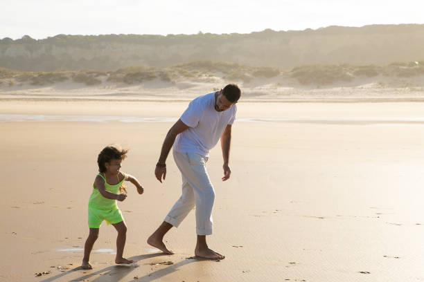 istock Handsome young dad and active little girl running on sand 1273278665