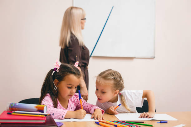 istock two happy little schoolgirls study in class, the teacher explains 1273278728