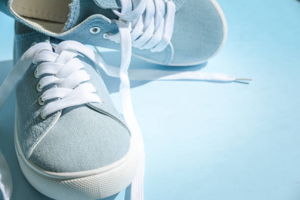 istock Blue sneakers with white laces on a light blue background. 1273279186