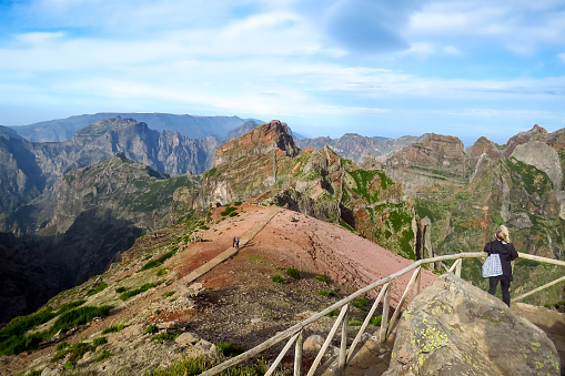 Pico Arieiro, Madeira, Portugal - 12/15/2015: Landscape view of Pico Arieiro mountain from the Juncal viewpoint (Miradouro do Juncal) and hikers on the trail, Madeira Island, Portugal, Europe