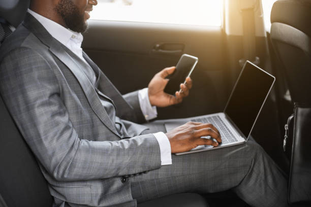 istock African american businessman using smartphone and laptop in car 1273281904