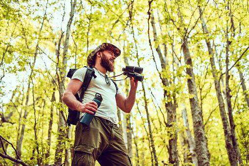 Smiling Hiker Using Binoculars During Forest Walk