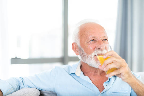 istock Happy senior man drinking juice and relaxing at home. 1273286100