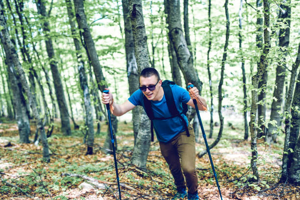 istock Smiling Male Hiker Using Sticks To Climb Uphill 1273286250