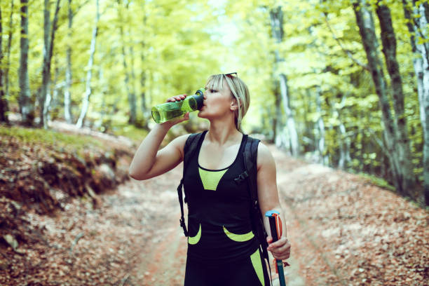 istock Cute Female Blond Hiker Drinking Water To Help Her Endure Forest Trip 1273286667