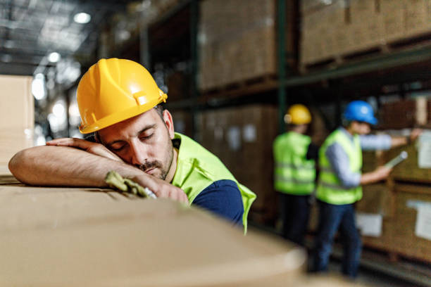 tired manual worker napping on carton boxes in storage room. - asleep on the job imagens e fotografias de stock