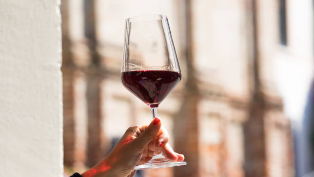 bicchiere di vino che tiene a mano - wine bottle bottle burgundy wine foto e immagini stock