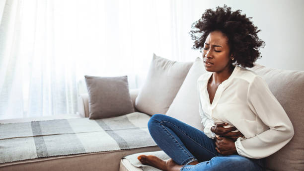 istock Young woman suffering from abdominal pain while sitting on sofa at home 1273292583