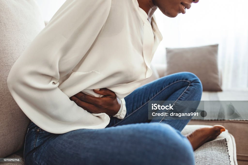 Ouch! My tummy! Cropped shot of an attractive young woman lying on her sofa alone and suffering from period cramps at home. Ouch! My tummy! Woman with menstrual pain Stomachache Stock Photo