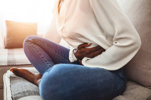 Ouch! My tummy! Young sick woman with hands holding pressing her crotch lower abdomen. Medical or gynecological problems, healthcare concept. Young woman suffering from abdominal pain while sitting on sofa at home irritable bowel syndrome stock pictures, royalty-free photos & images