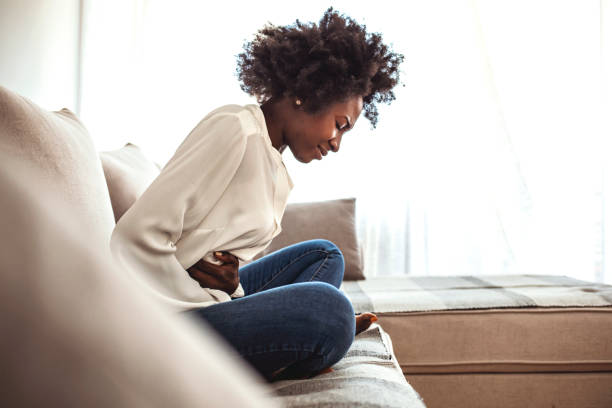 istock Woman sitting on bed and having stomach ache. 1273292869