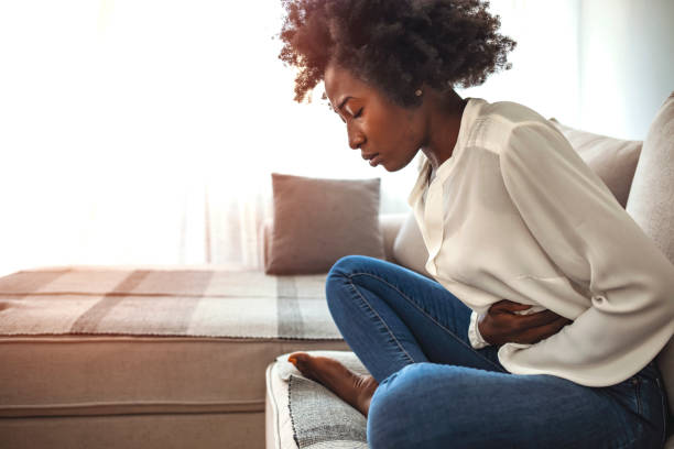 istock Woman sitting on bed and having stomach ache. 1273292940