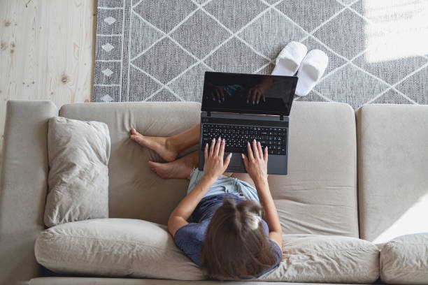 istock Young woman sitting on sofa and using laptop at home 1273293085