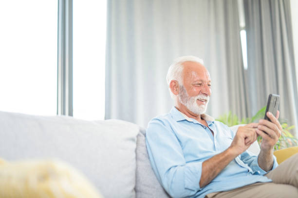 istock Happy senior man using phone in the living room. 1273293696