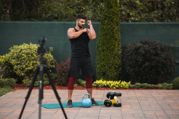 istock Male athlete doing exercise in backyard and filming vlog. 1273294243