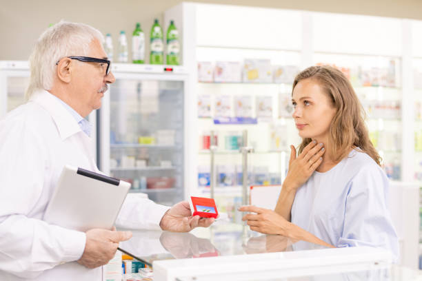 istock Young blond female client touching her sore throat while asking for medicaments 1273296486