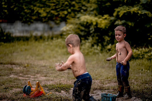 Little boys playing in muddy ponds