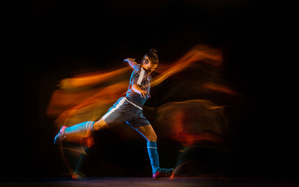 istock Football or soccer player on black background in mixed light, fire shadows 1273297832