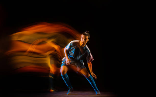 istock Football or soccer player on black background in mixed light, fire shadows 1273297834